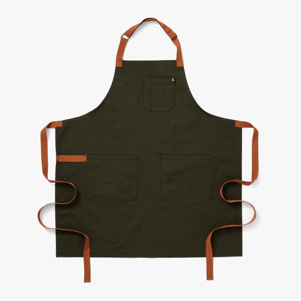 Iconic. Classic. Timeless. Nothing like our fan-favorite olive apron body with brand-new cider straps and a navy ampersand to remind you of the natural colorways of Summertime grillin' in the trees by the lake.
